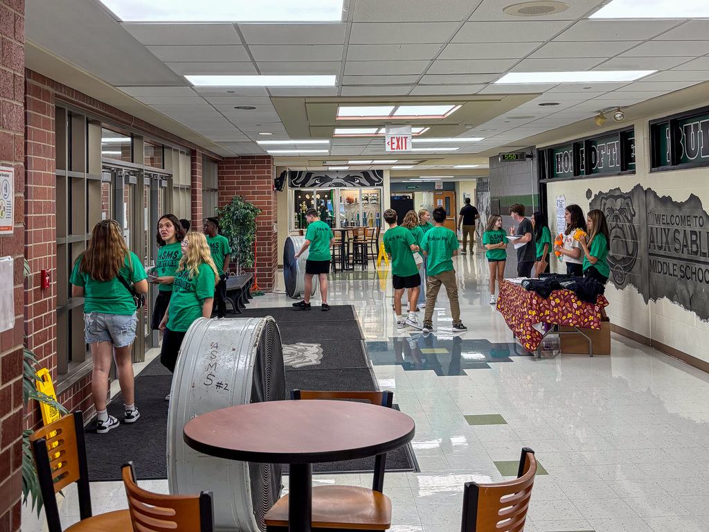 group of middle school students wearing green T shirts standing in hallway