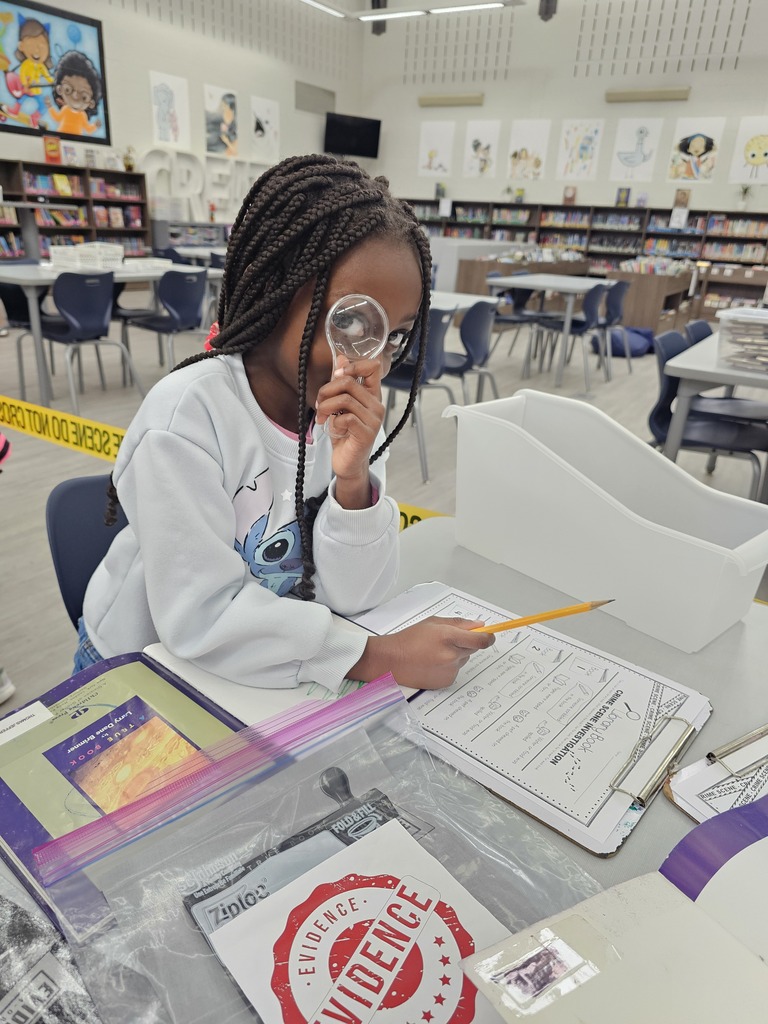 A student looking through a magnifying glass at a book.