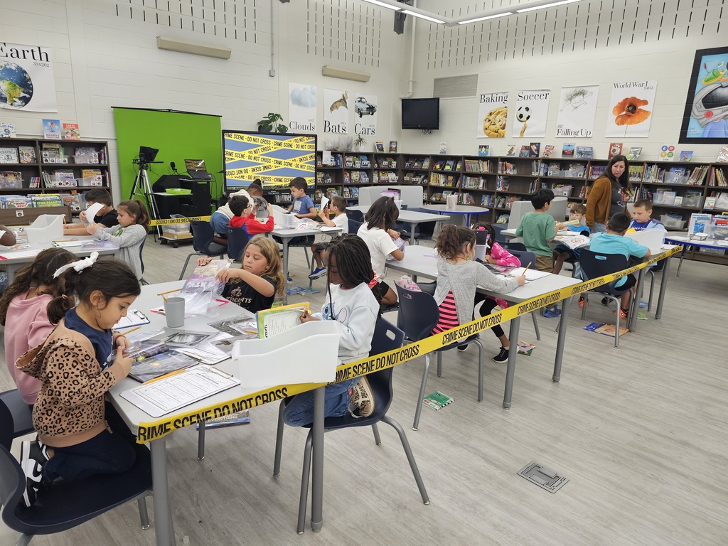 Students in a library looking at books with a magnifying glass.