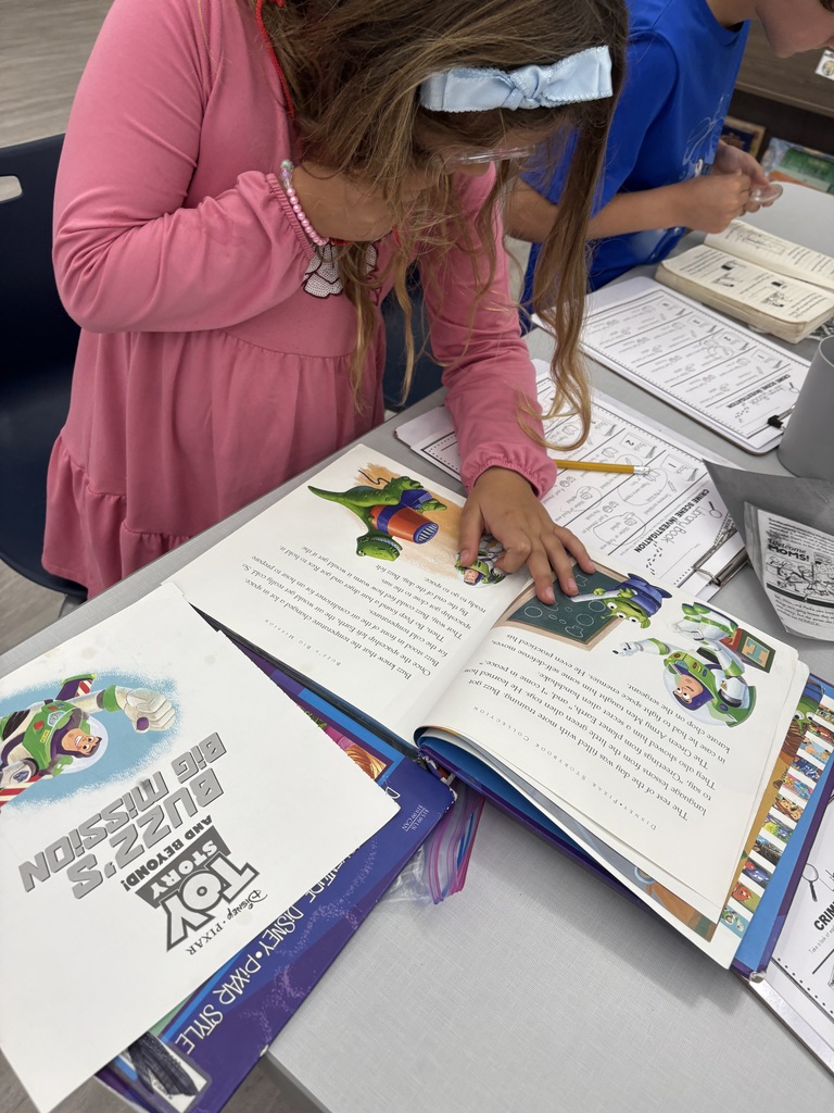 A student looking through a magnifying glass at a book.
