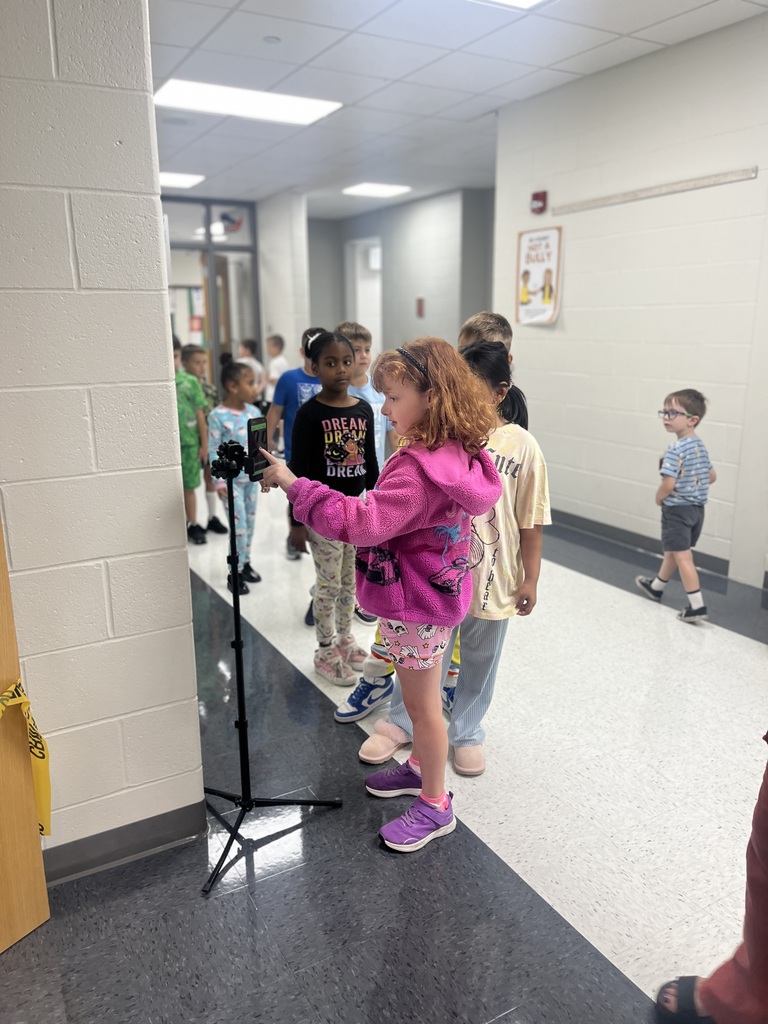 Student is using a pretend finger scan on a phone in a hallway.