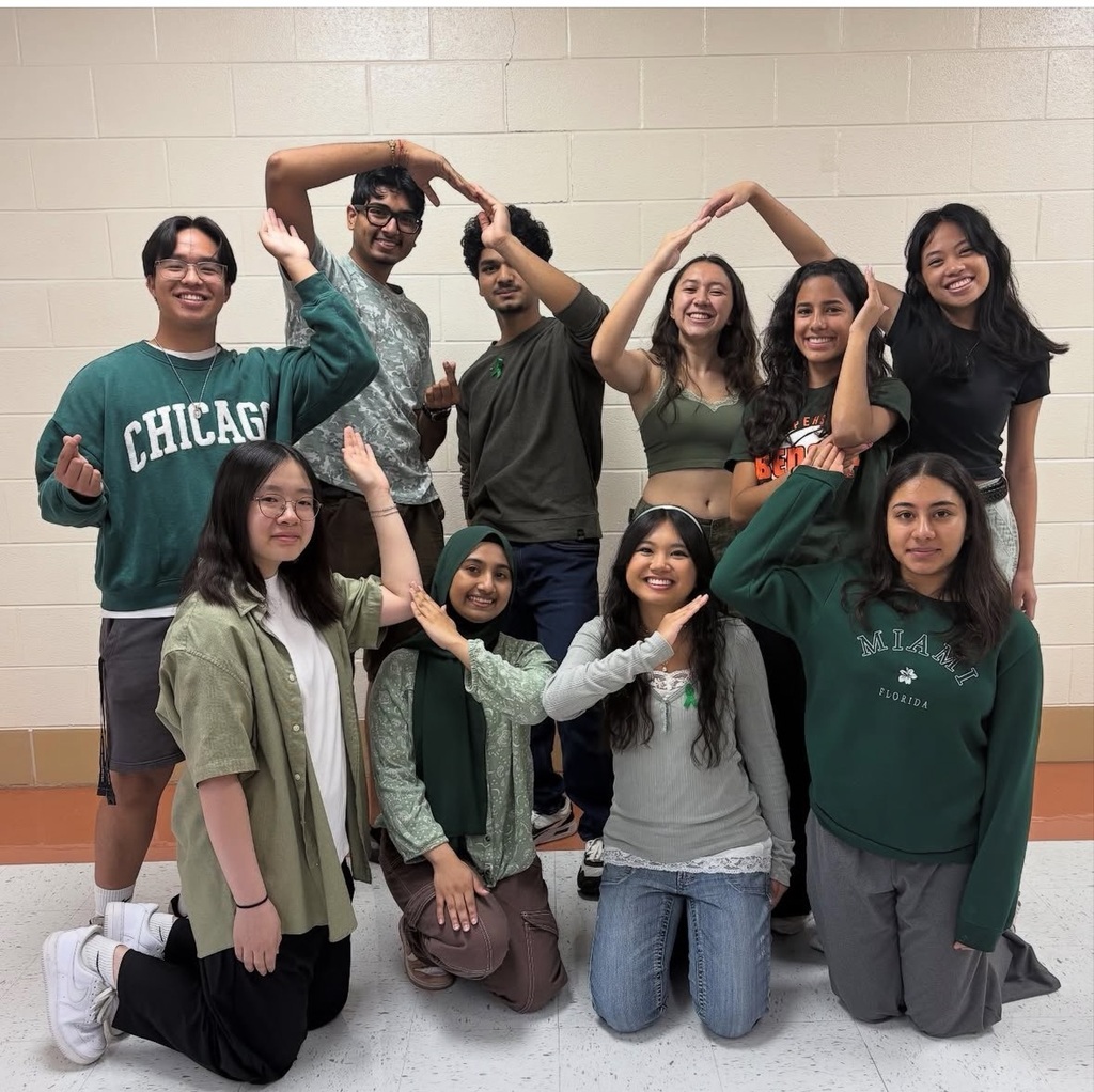 students inside using their arms to form a heart shape