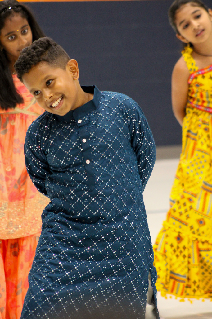 boy dressed in blue robe with pattern on it dances and smiles