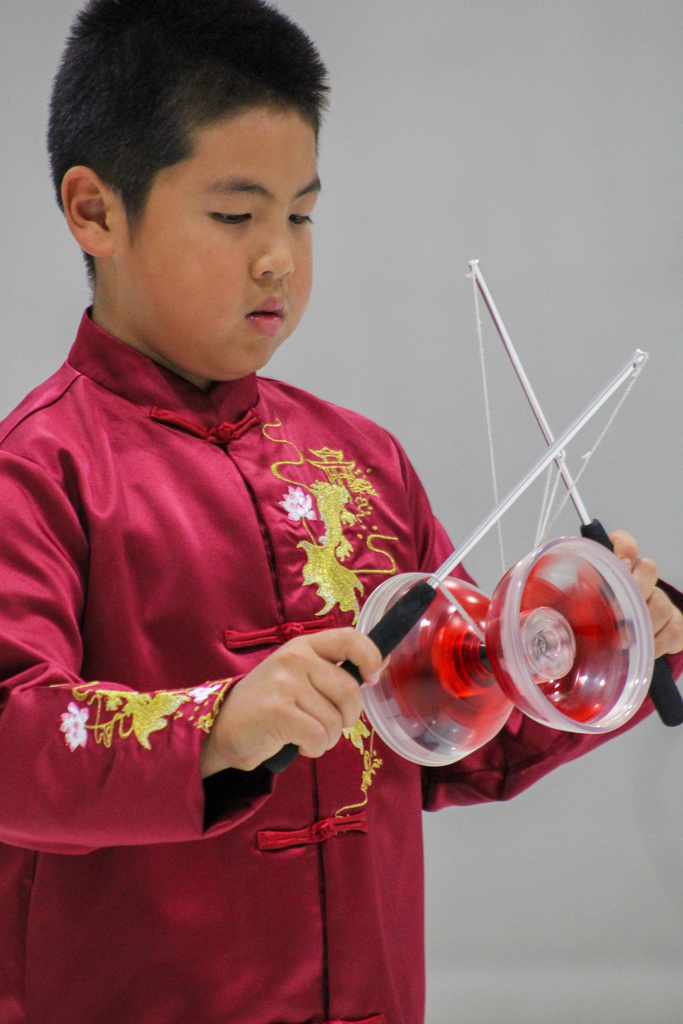 boy dressed in red robe performs with Chinese yoyo