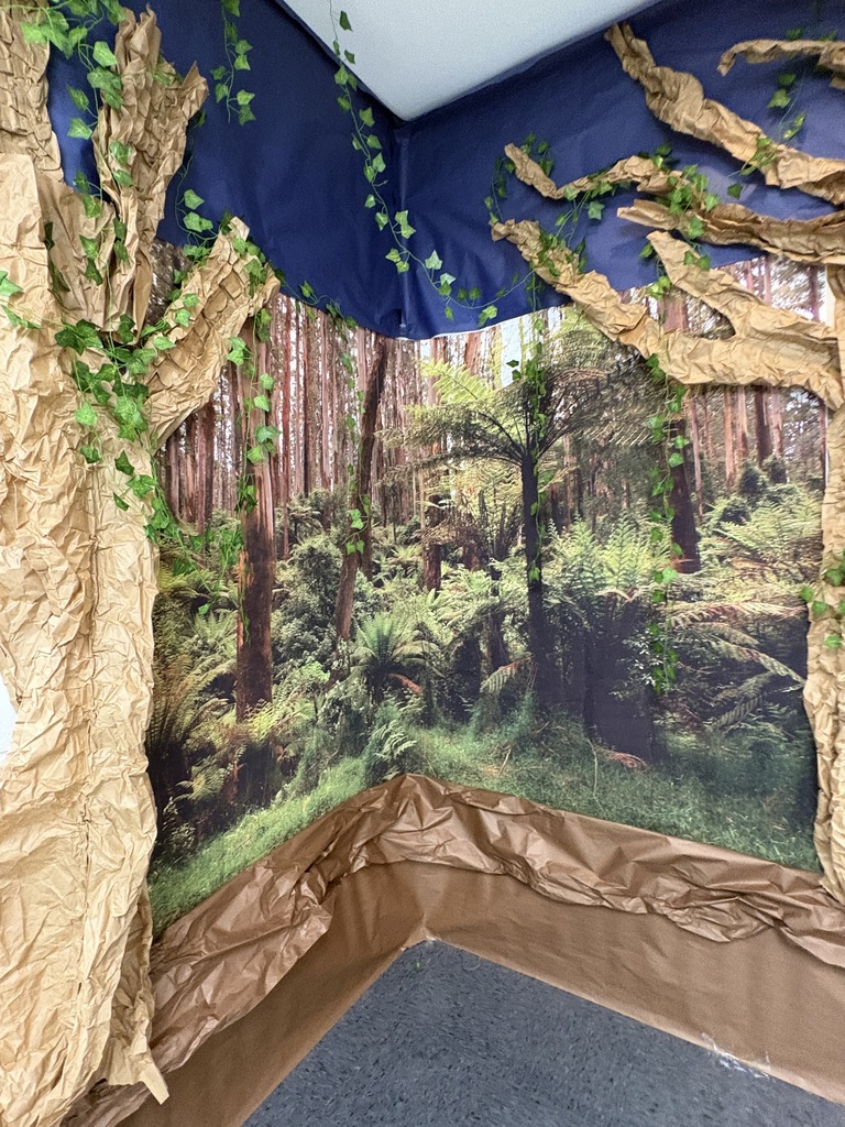 A doorway of an elementary school library decorated like a forest.