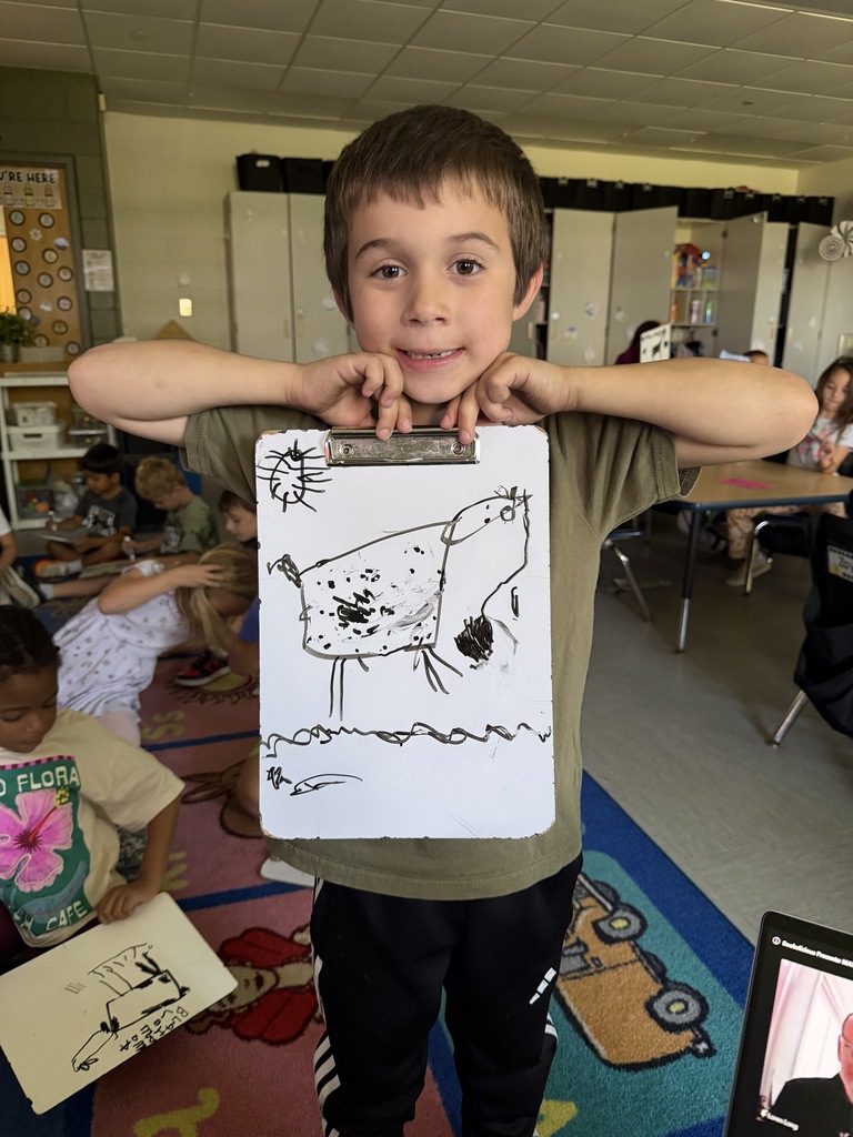 A student shows a goat, drawing on a dry erase board.