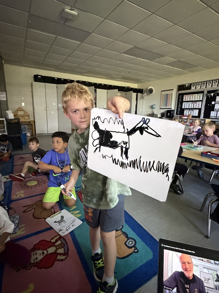 A student shows a goat, drawing on a dry erase board.