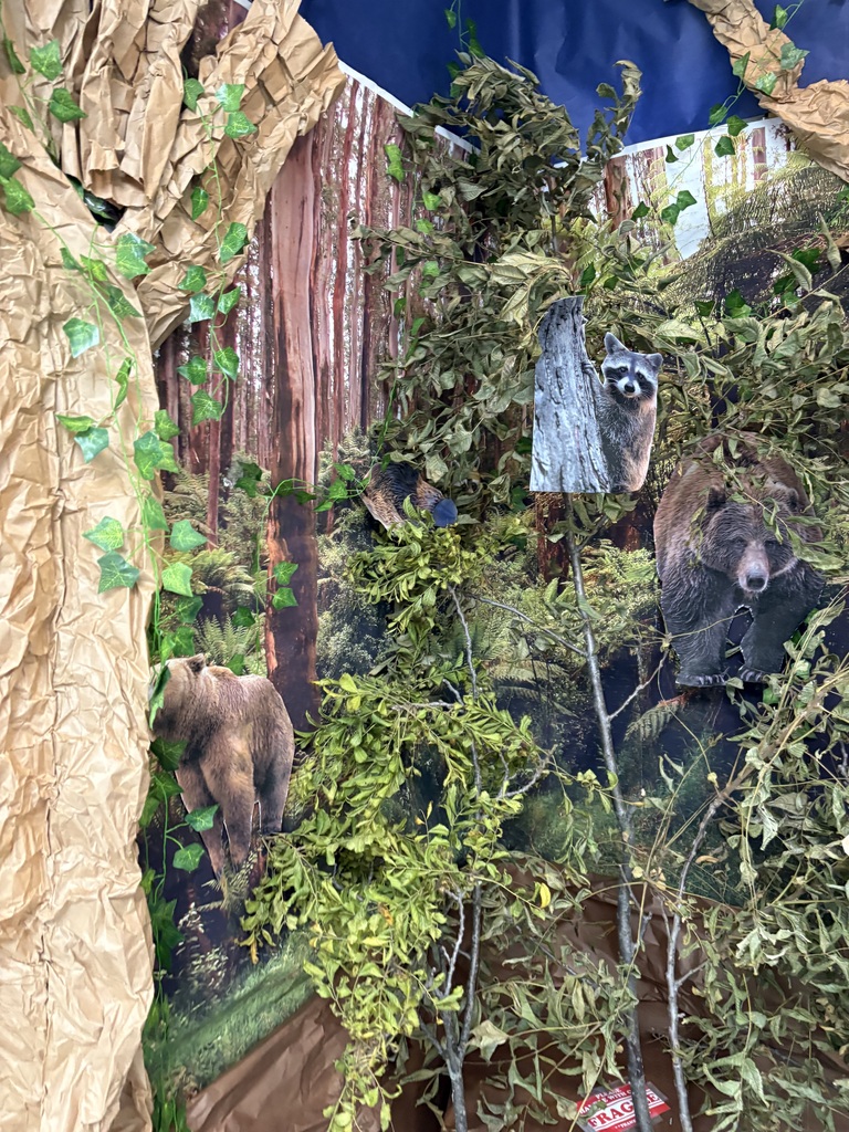 A hallway display with a forest, backdrop and paper animal cut outs.