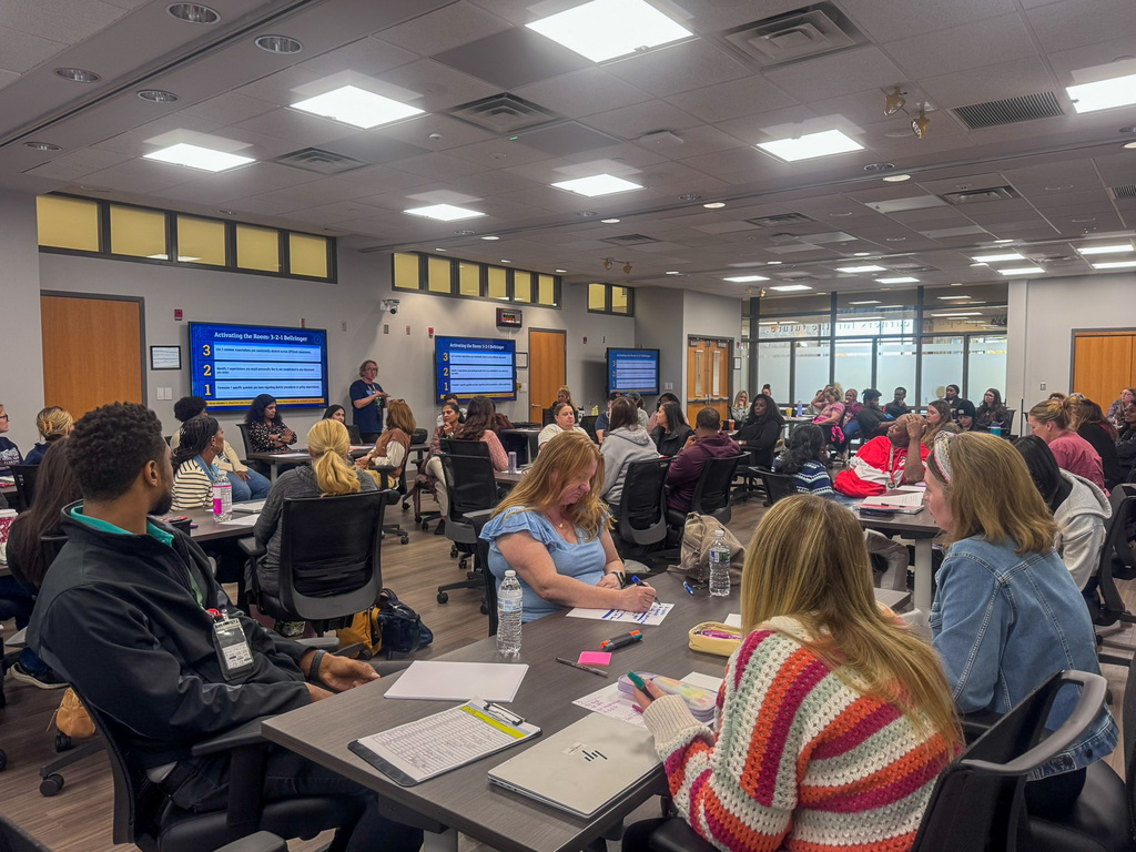 group of adults in room sitting at tables writing