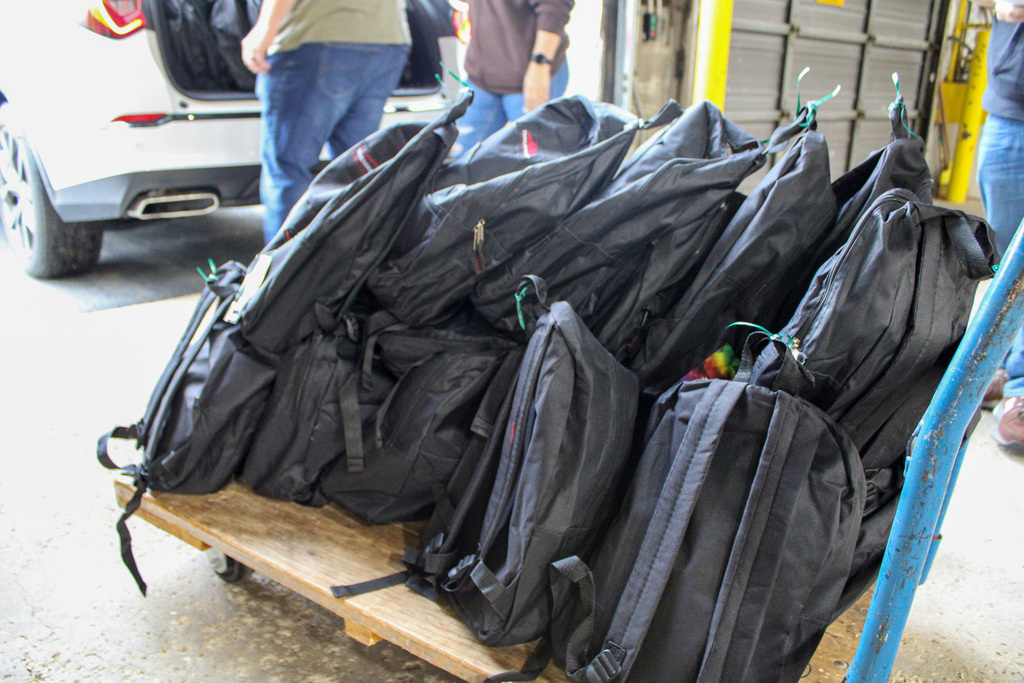 backpacks sit on a pull cart with a blue handle