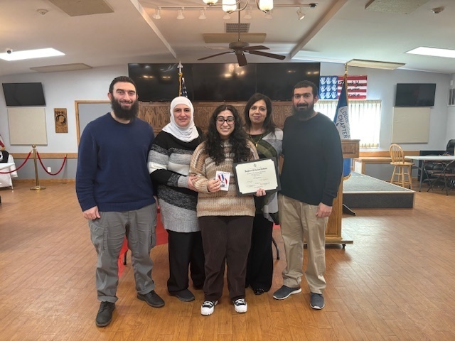 group photo of student holding awards with family around her