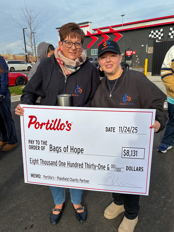 two woman holding oversized check Portillos' Bags of Hope $8,131