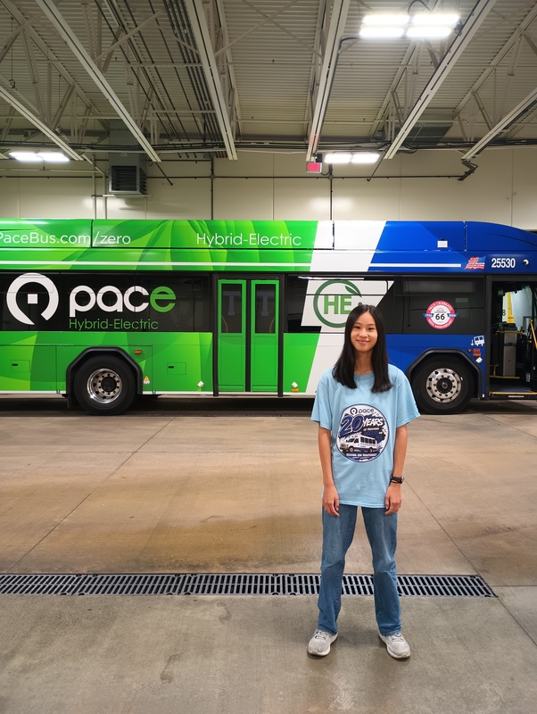 Plainfield North High School senior Madeleine Yui stands alongside a Pace bus during her summer internship with Pace Suburban Bus.  
