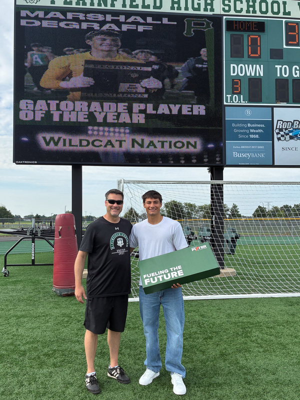 adult stand with student who is holding sign