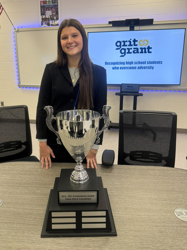 woman stands behind trophy