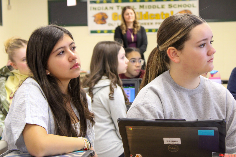 two middle school studetns looking to the right with laptop in front of them