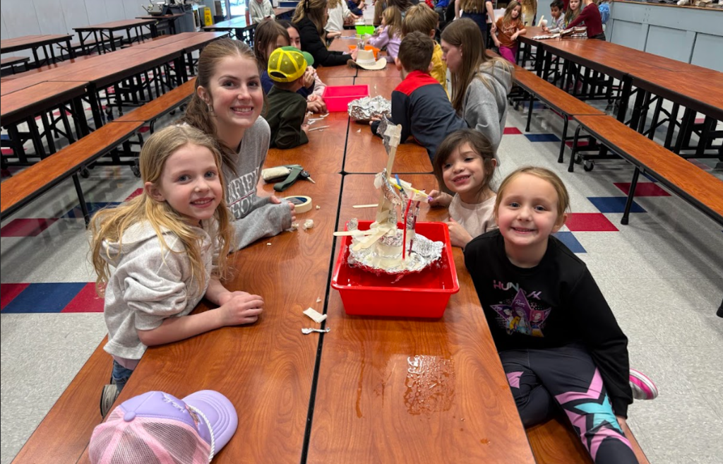 High school HOSA students helping kindergarteners build a boat