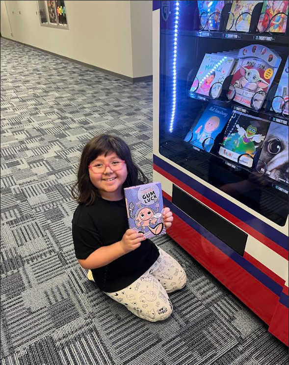 Student posing with book from vending machine