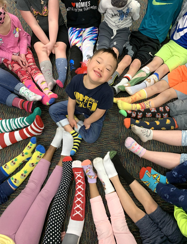 At Clarks Creek, Kindergarten students surround their friend with their brightly-color socks as part of the #LotsOfSocks celebration At Clarks Creek, Kindergarten students surround their friend with their brightly-color socks as part of the #LotsOfSocks celebration