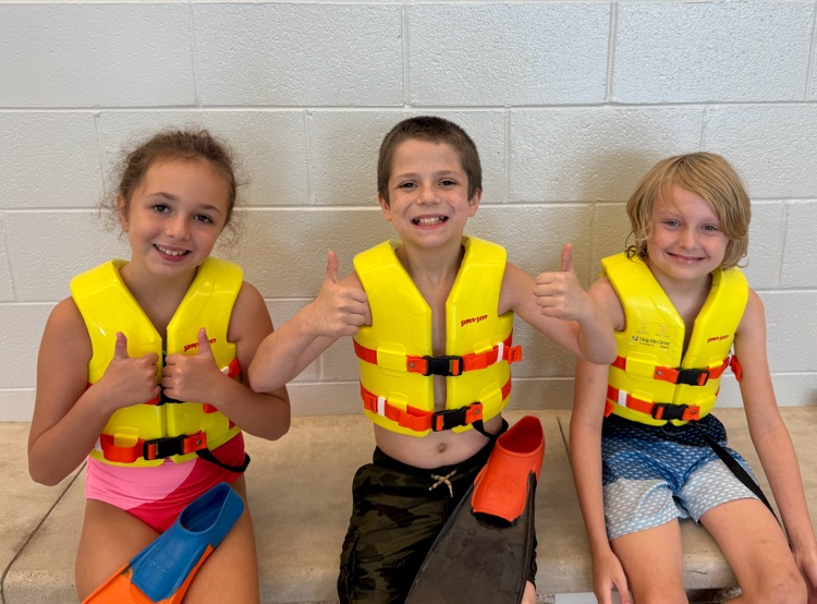 picture of three students at the pool showing their life jackets
