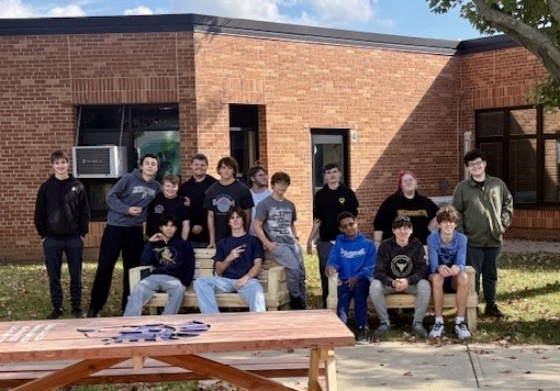 picture of group of students on benches that they built in woodshop class