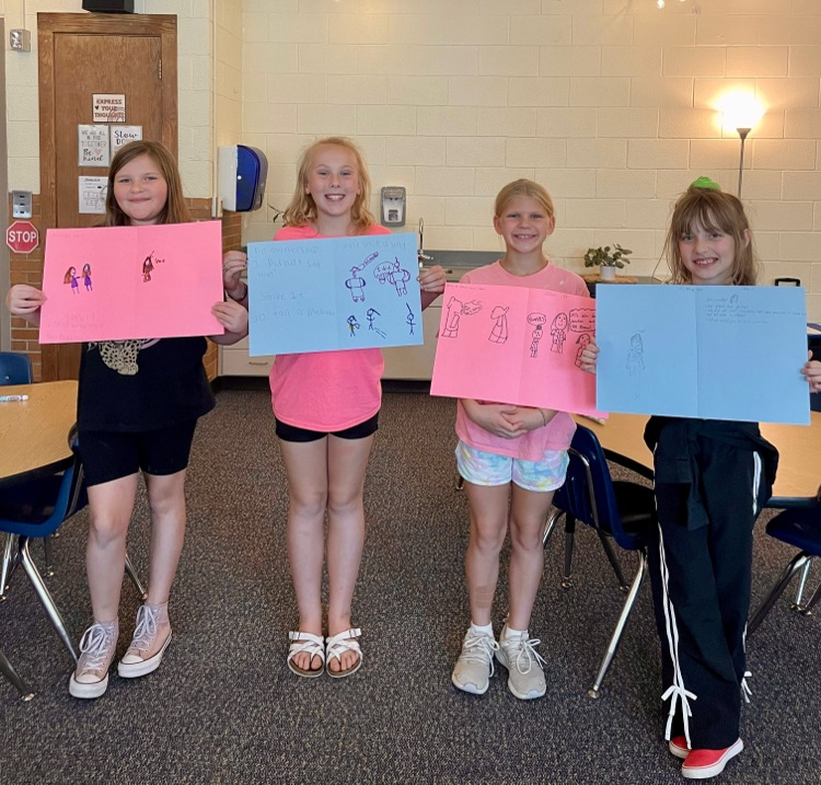 picture of four cooper students holding posters they created