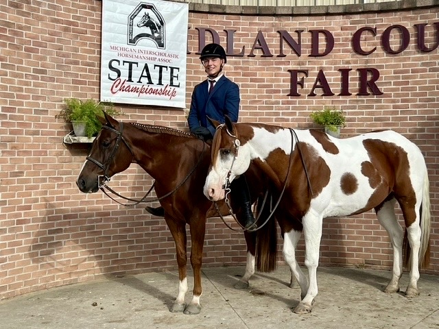 picture of a student with two horses at a competition