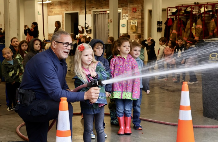 picture of a student spraying water on a field trip to the fire station 