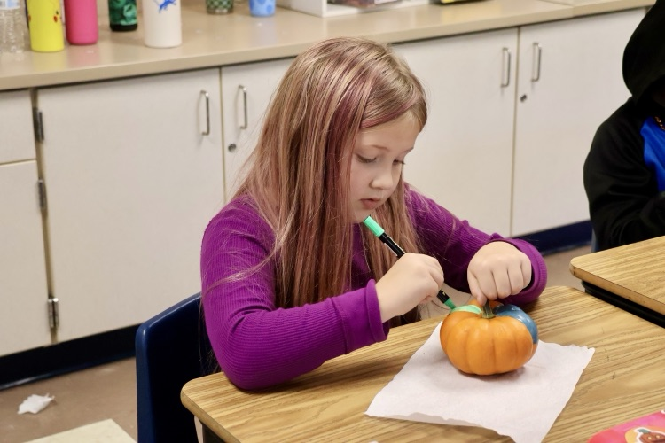 picture of student coloring a pumpkin 