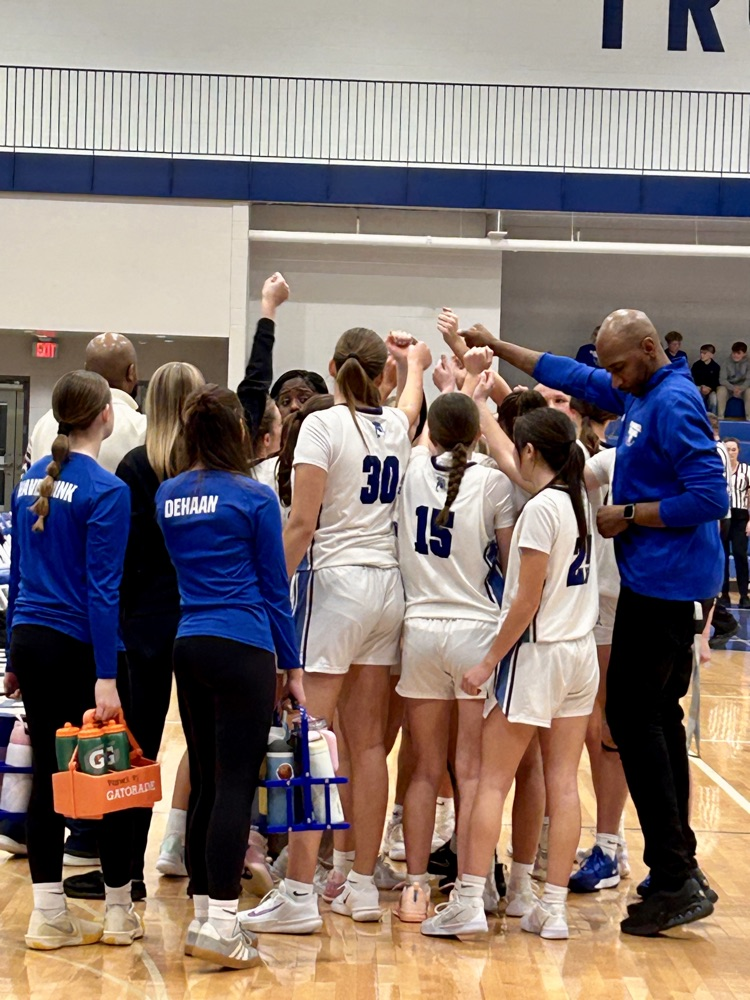 picture of varsity girls basketball team in a huddle 