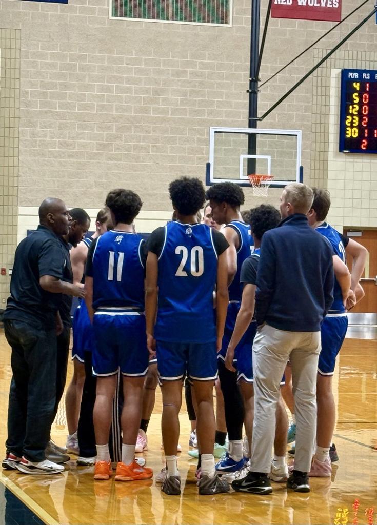 picture of phs varsity boys basketball team in a huddle 