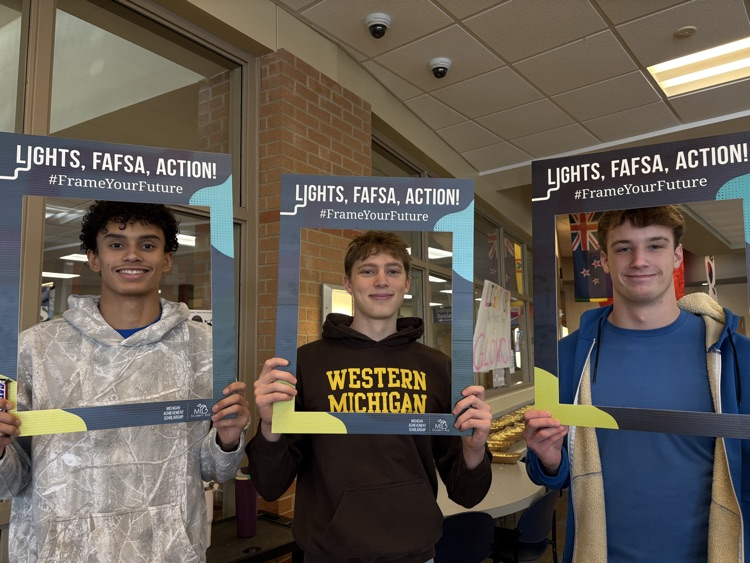 picture of three students holding FAFSA signs
