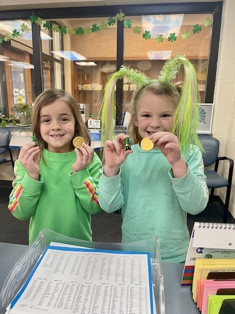two students holding up gold coins for st Patrick’s day