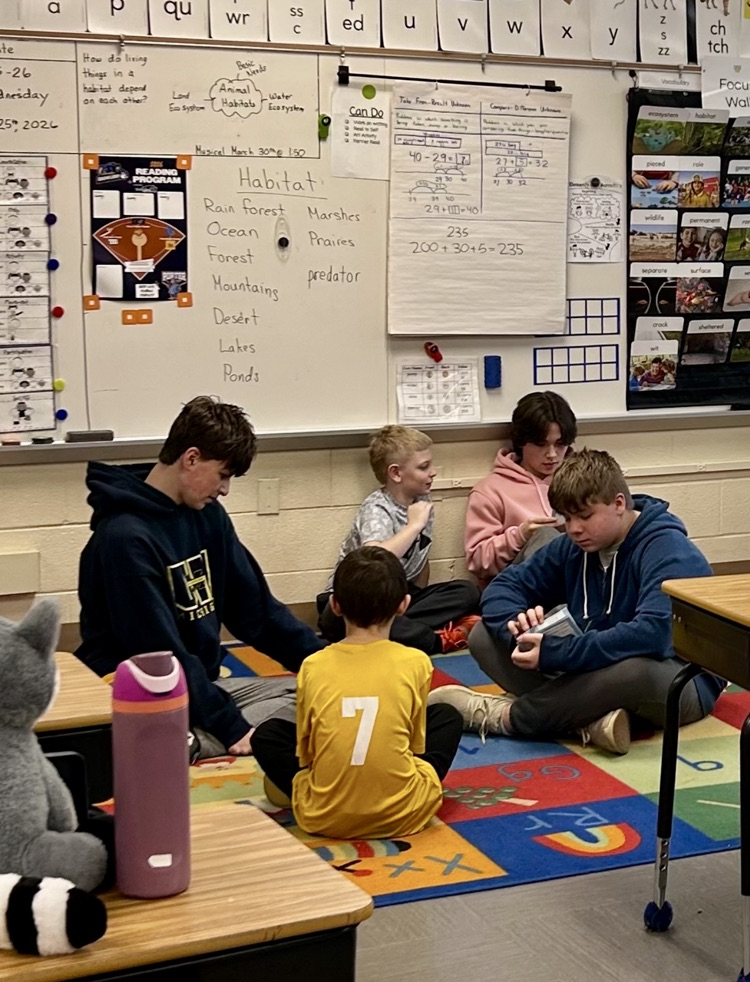 middle school students reading to second graders during reaching month