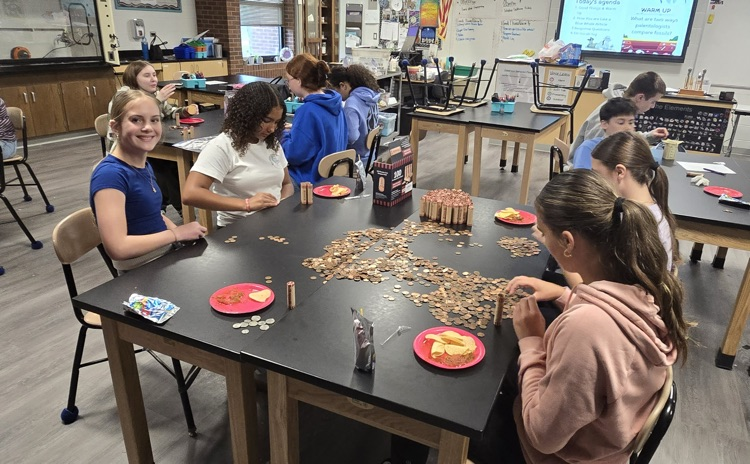 picture of group of NJHS students sorting money collected during their penny war fundraiser 