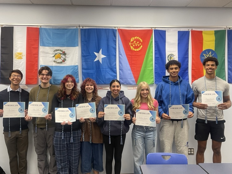 picture of 8 senior multicultural club students holding those certificates of recognition and wearing their multicultural club cords for graduation