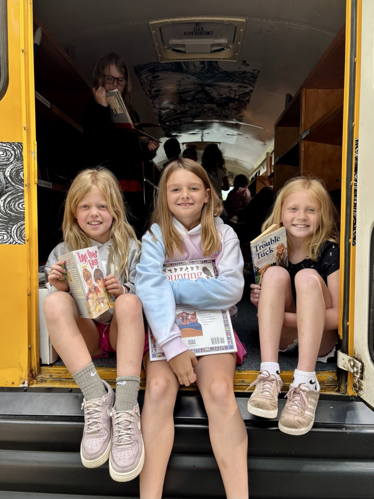 picture of three students holding books on the book bus