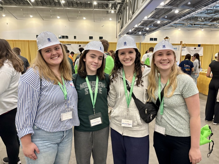picture of four students with hard hats on at a career quest event