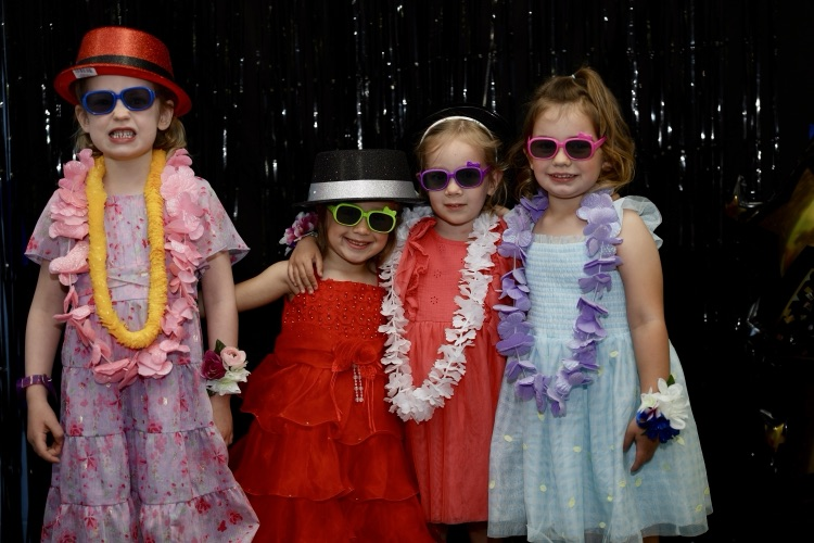 four students dressed up in a Photo Booth at their preschool prom