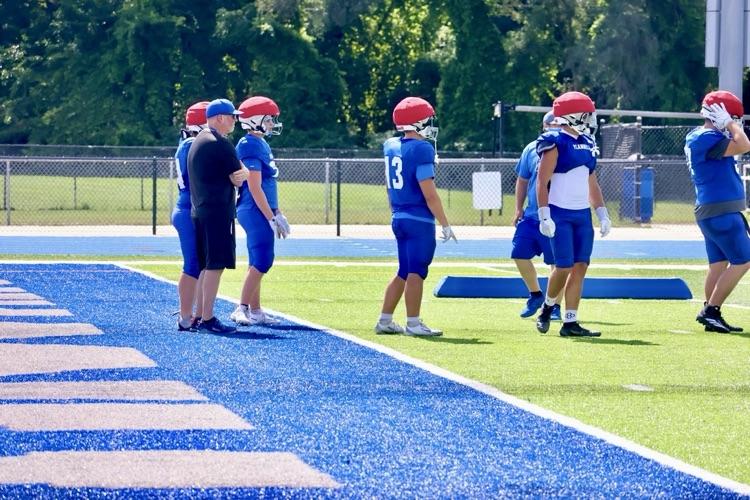 picture of superintendent Montange helping the football team at practice