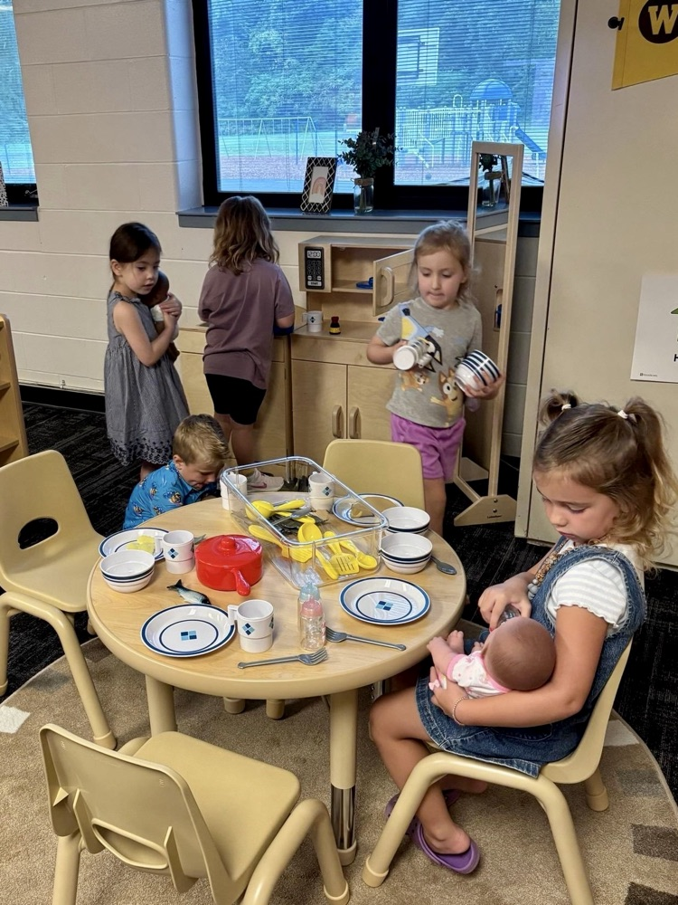 picture of group of preschool students playing in a play kitchen and with dolls