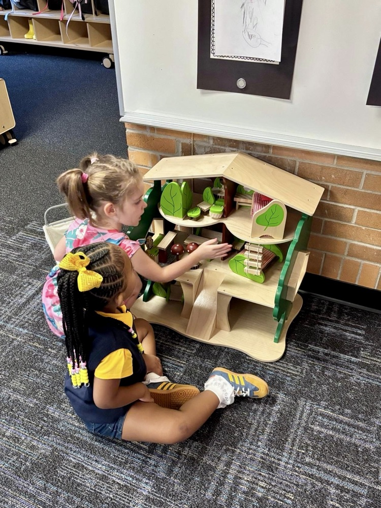 picture of two preschool students playing with a dollhouse 