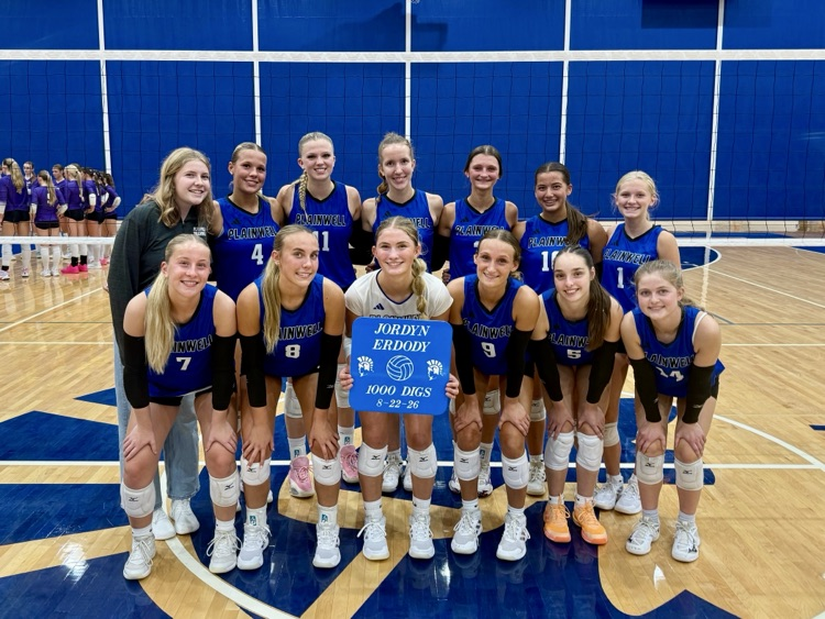 picture of varsity volleyball team with athlete holding a plaque for her 1,000th career dig