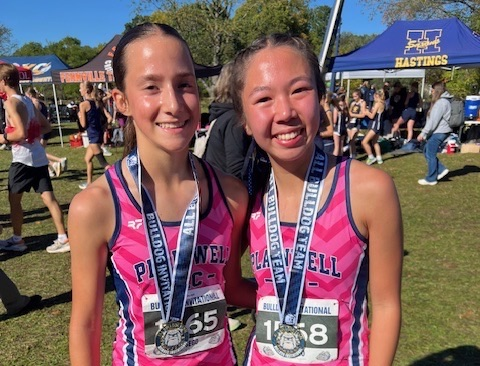 picture of two cross country runners with medals