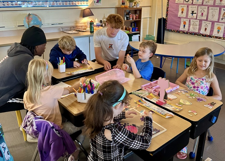picture of Kalamazoo college soccer players working on a craft activity with elementary students