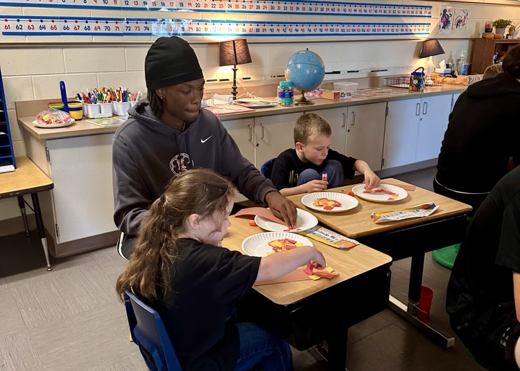 picture of Kalamazoo college soccer players working on a craft activity with elementary students
