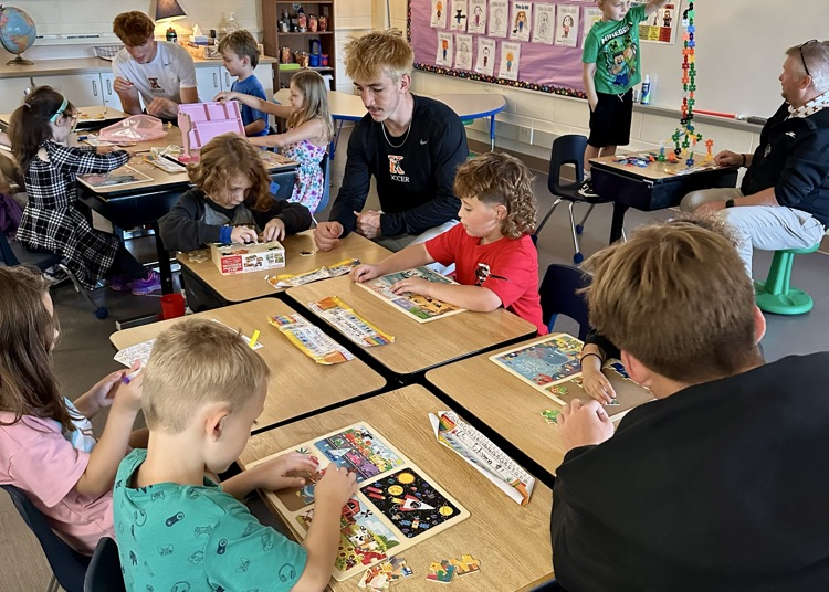 picture of Kalamazoo college soccer players working on a craft activity with elementary students