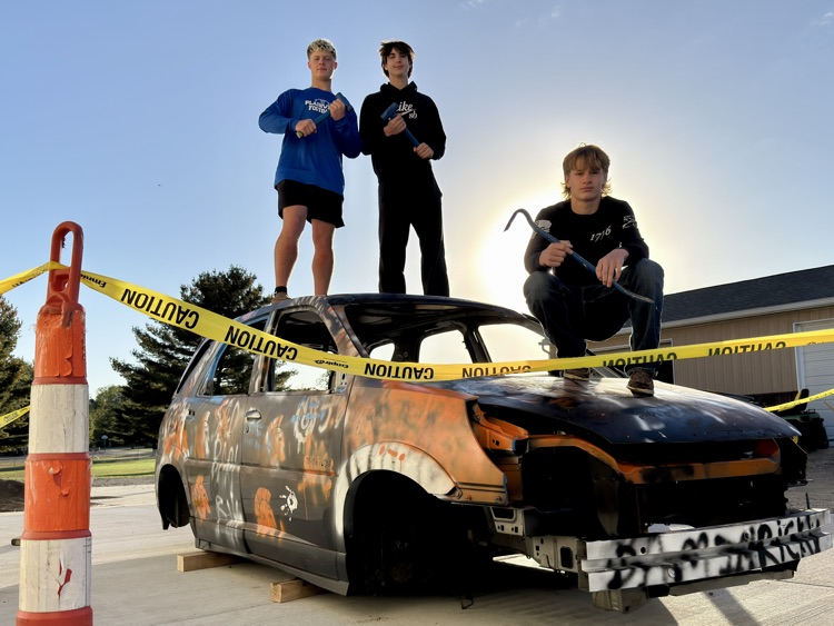 picture of auto reach students standing on a car they disassembled for homecoming spirit week