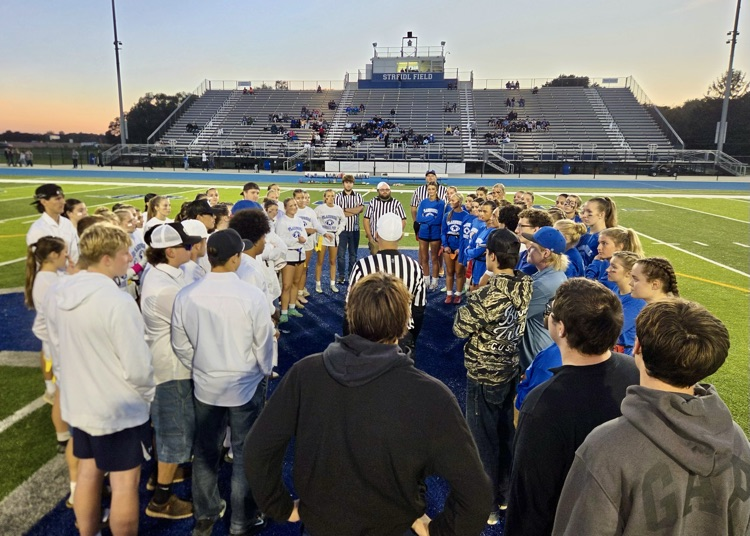 picture of Junior and Senior powderpuff football teams facing off in a huddle before game