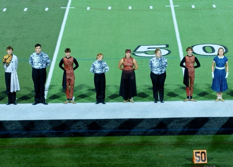 picture of 8 Trojan marching band students standing in a line